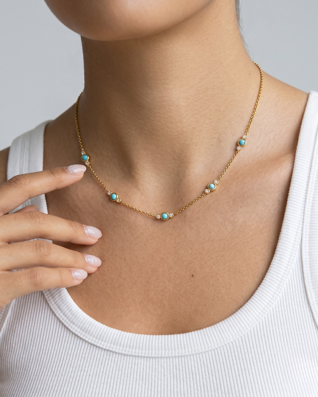 Isla necklace worn at the collarbone, 18k gold plated chain interrupted by turquoise and crystal stones