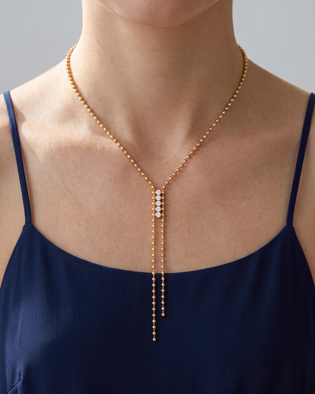 Lyra necklace worn at the neckline, fine 18k gold plated ball chain lariat with Y-shaped drop falling below the collarbone
