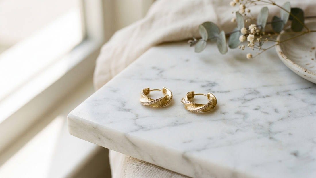 Elegant gold earrings on white marble — milestone jewellery meaning and significance by Clarabelle