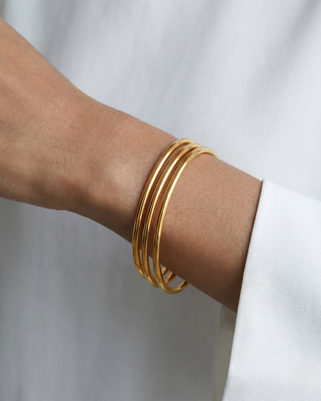 Amélie bangle worn on the wrist, clean tubular round silhouette
Stacked shot: Amélie bangles stacked on the wrist, gold  finish 
