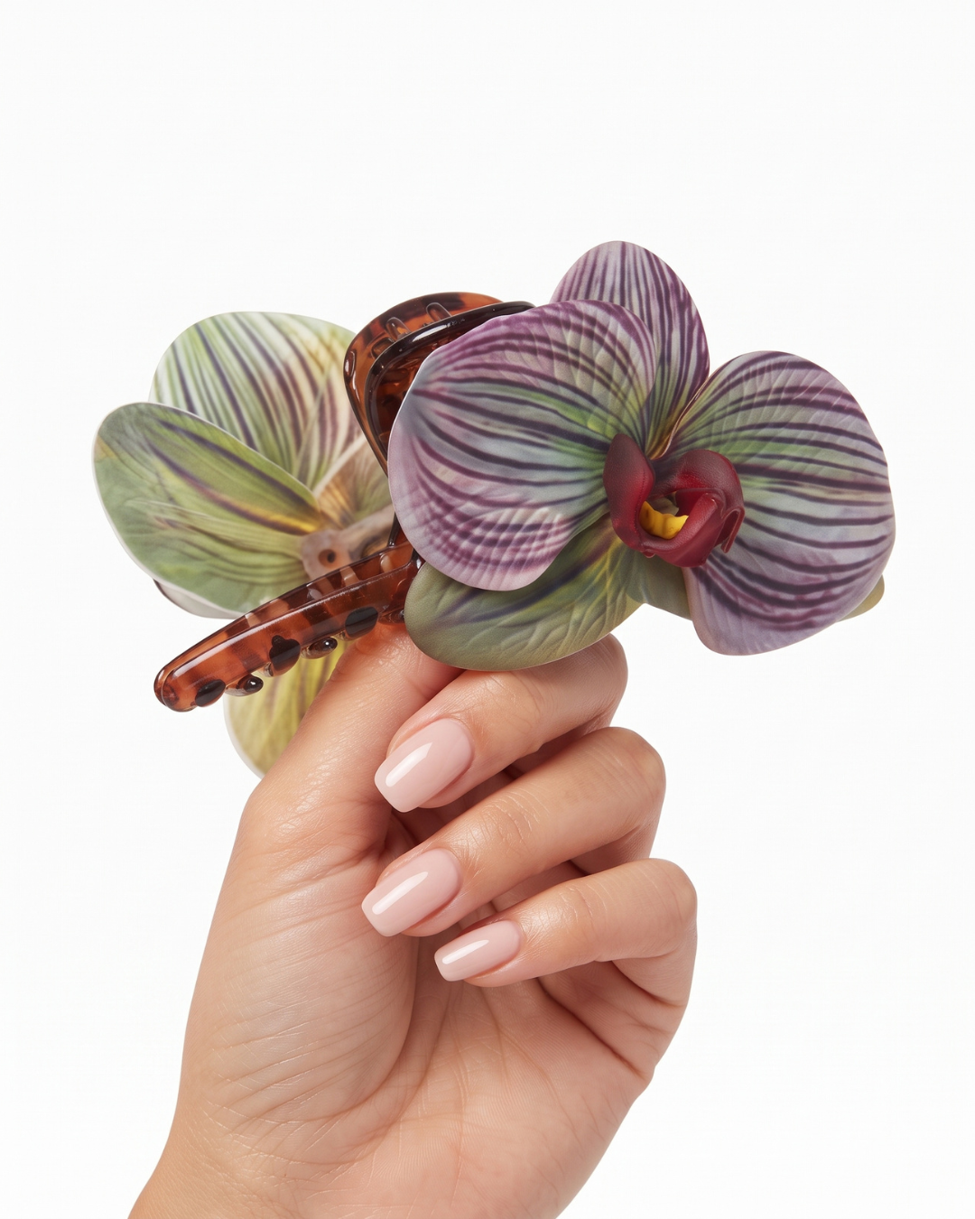 Bianca sculpted orchid hair clip in striped purple and green with crimson centre, held to camera on neutral background