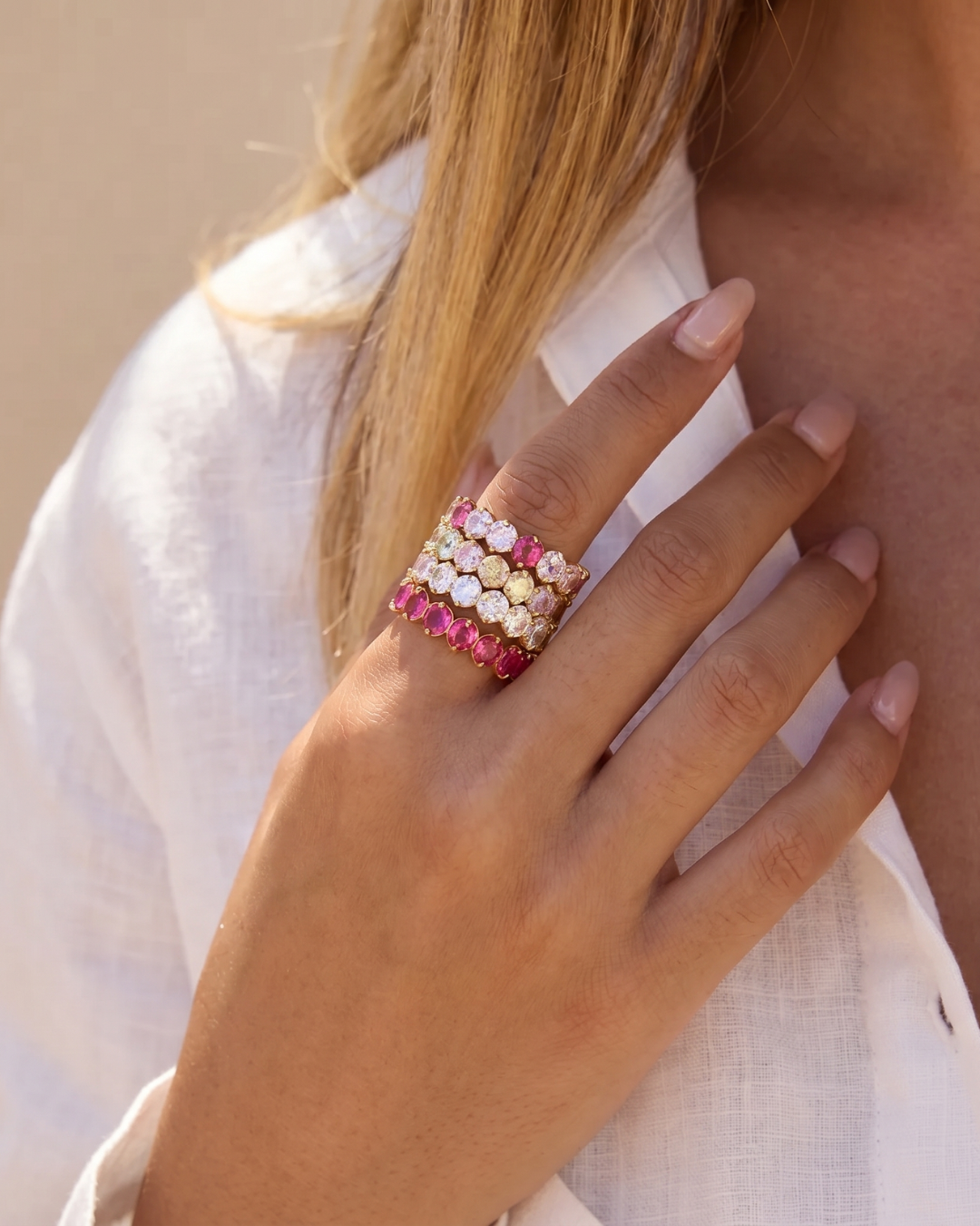 Stacked 18K gold zircon eternity band rings in white, hot pink and pastel multicolour worn on hand by Clarabelle