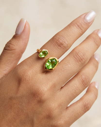 Gold open ring with dual green geometric gemstones worn on hand by Clarabelle