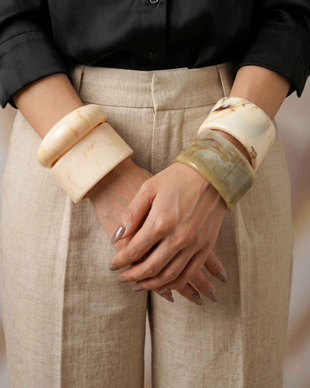 Marbre Bracelet handmade marble resin bangles in ivory and warm beige stacked on both wrists hands clasped in front worn with black shirt and linen trousers