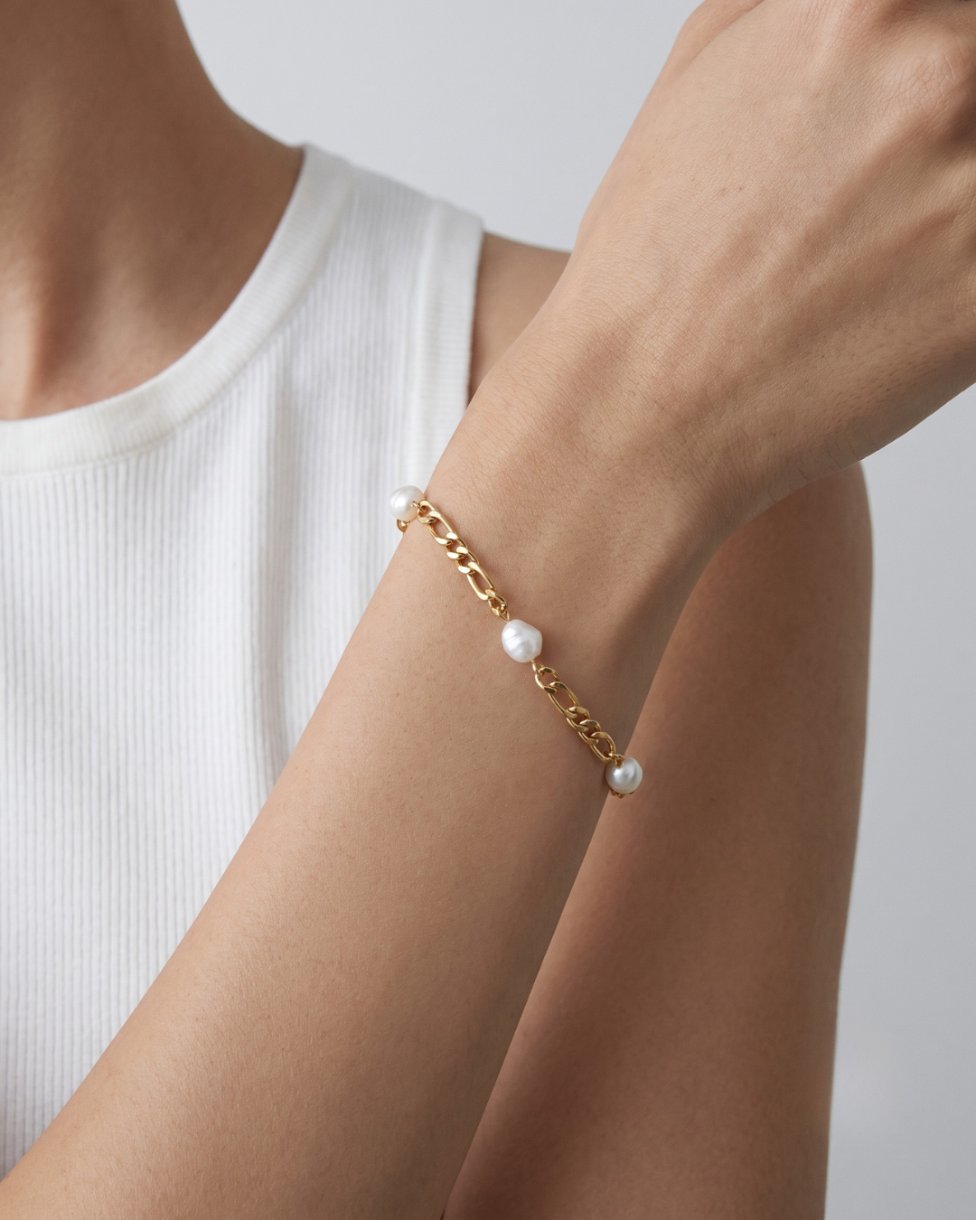 Marisol bracelet worn on the wrist, Figaro chain with baroque pearl drops in 18k gold plating