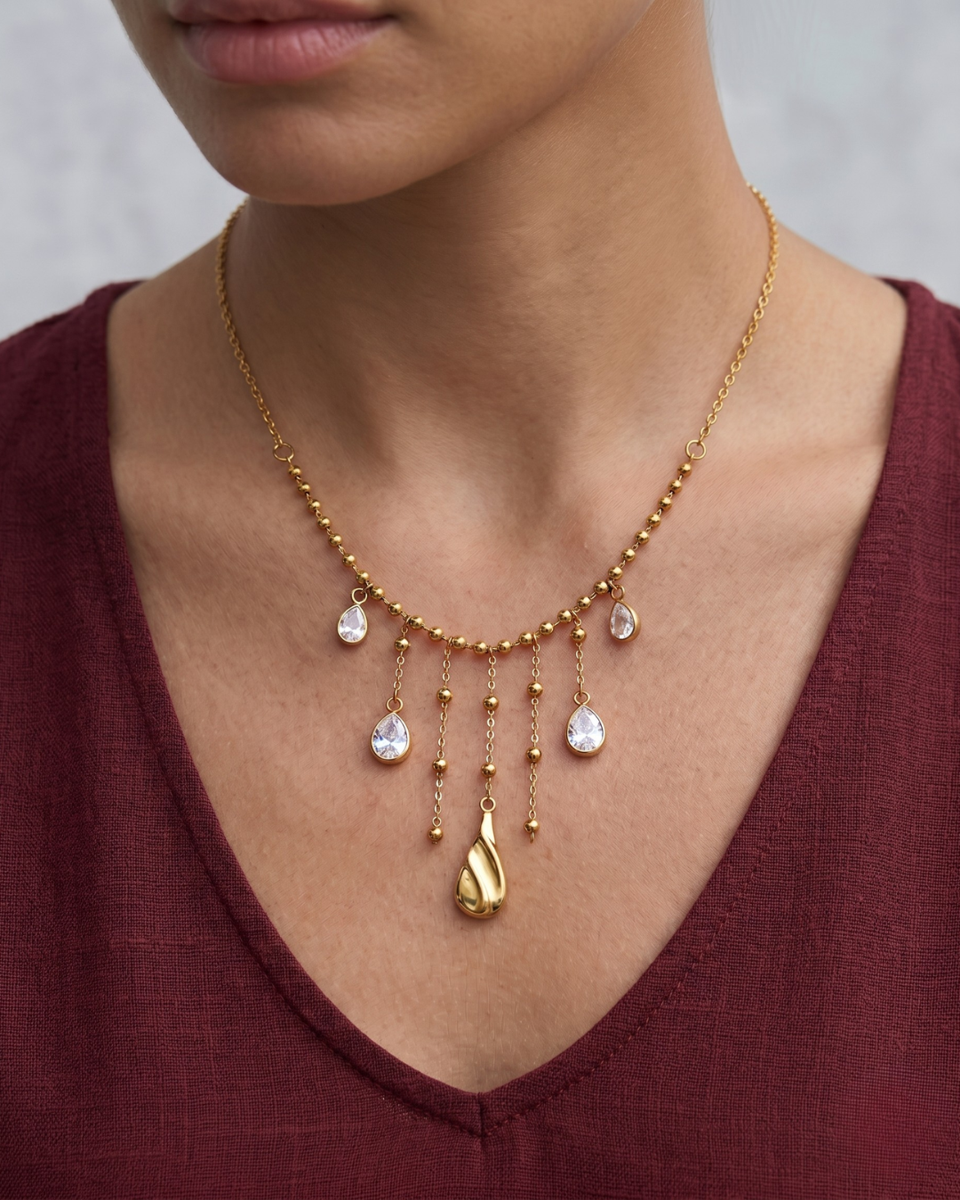Gold PVD stainless steel ball chain necklace with stone-effect water drop tassel pendants and sculptural gold drop, wear by clarabelle model 