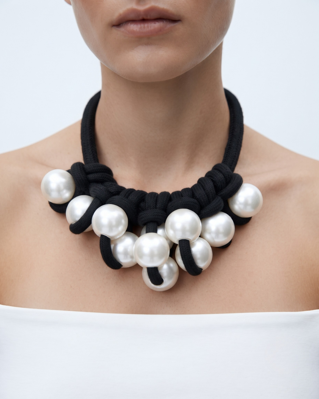 Simone necklace worn at the base of the throat, cluster of pearl pendants against black textile cord