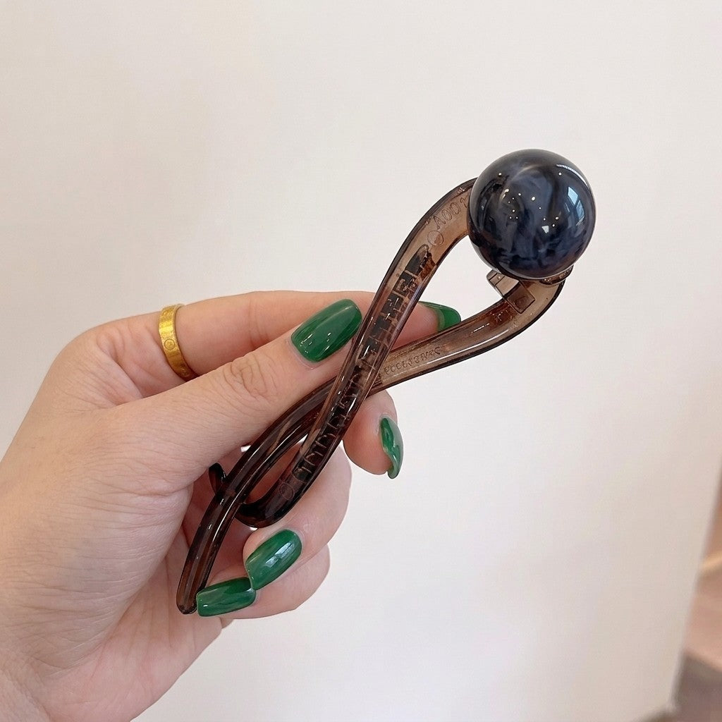 Suri twist bun holder in smoke with dark faux pearl bead, held to camera on neutral background