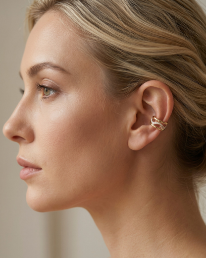 Woman wearing a gold wavy triple band ear cuff with stone-effect pavé detail, close-up on ear, minimal white top, soft natural light — Seoul Ear Cuff by Clarabelle