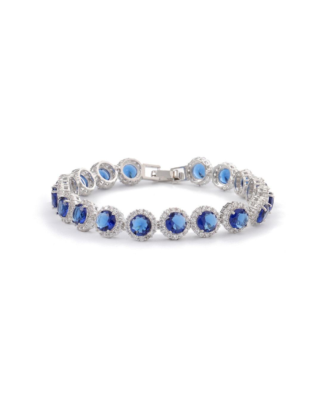 Zaira halo tennis bracelet with round sapphire blue zircon stones and clear pavé crystal halos on silver-tone plating, laid flat on neutral background