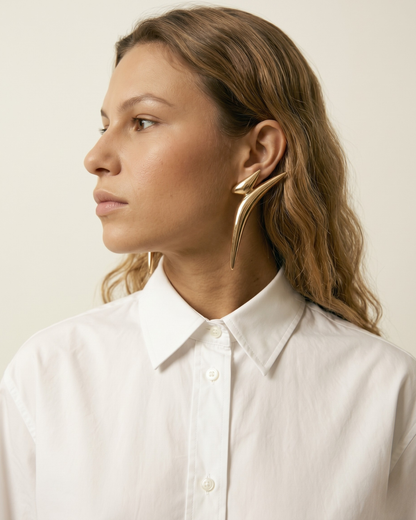 Side view of model wearing bold gold statement earrings with clean modern styling