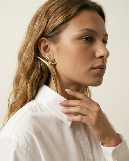 Model wearing long gold statement earrings with modern editorial styling