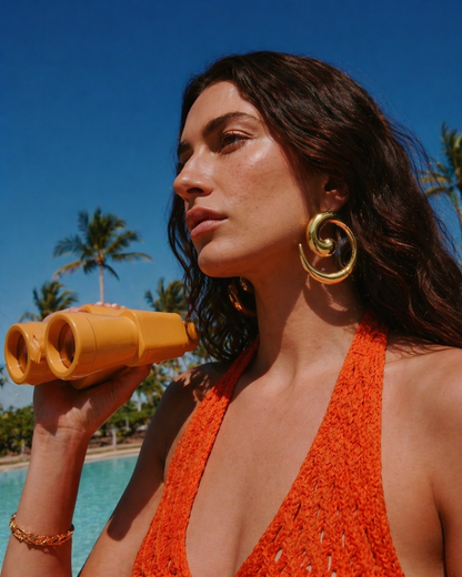 Model wearing gold statement earrings with summer outfit by the pool, bold jewellery styling