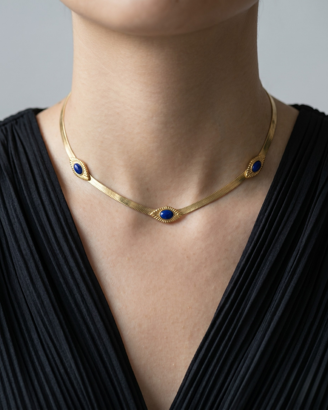 model wear a stainless steel herringbone chain necklace with three blue oval stone-effect pendants by Clarabelle